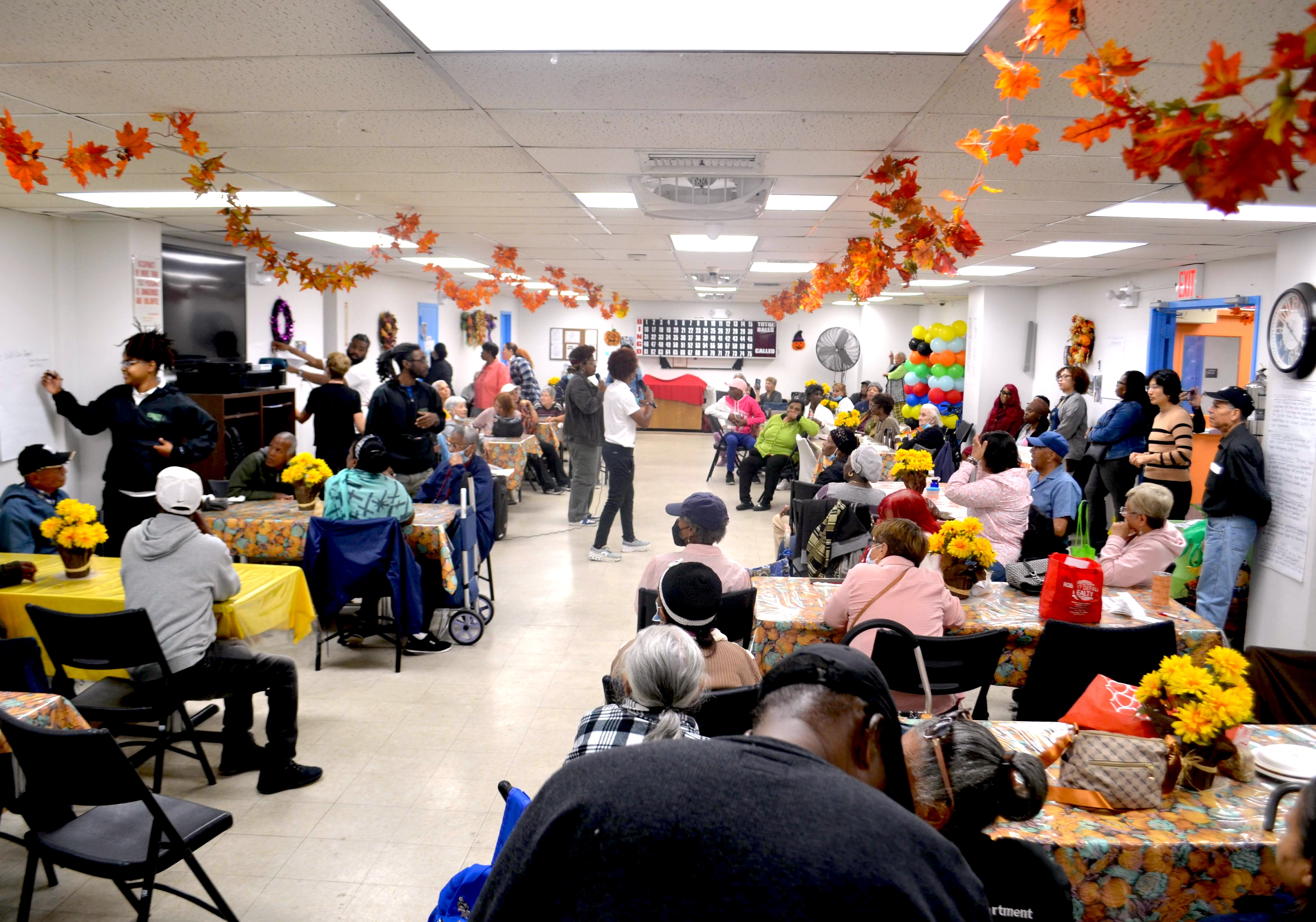 Diverse group of students and community members in a classroom setting listening to a presenter