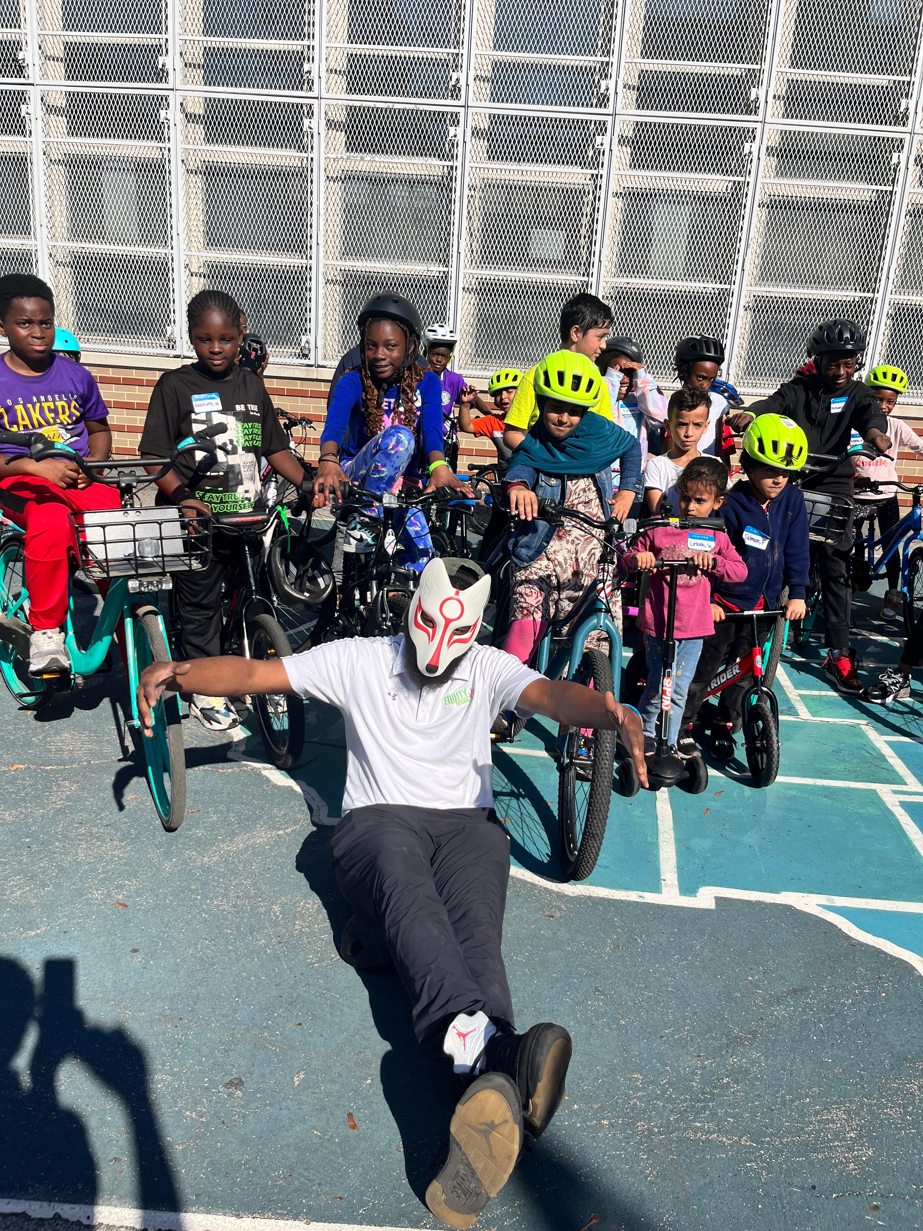Children with bicycles and helmets with an instructor demonstrating cycling skills