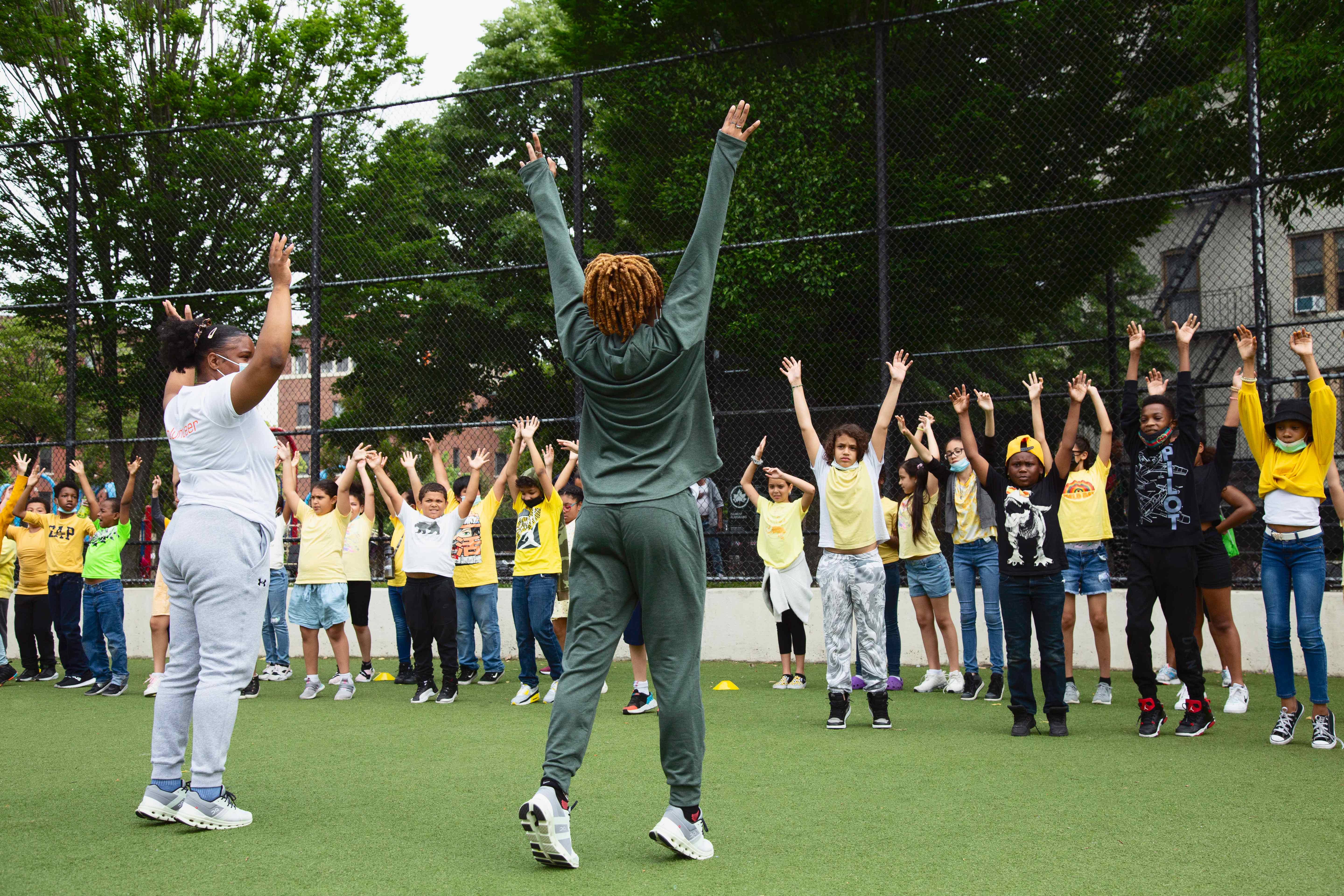 Instructors leading children in physical activities with arms raised