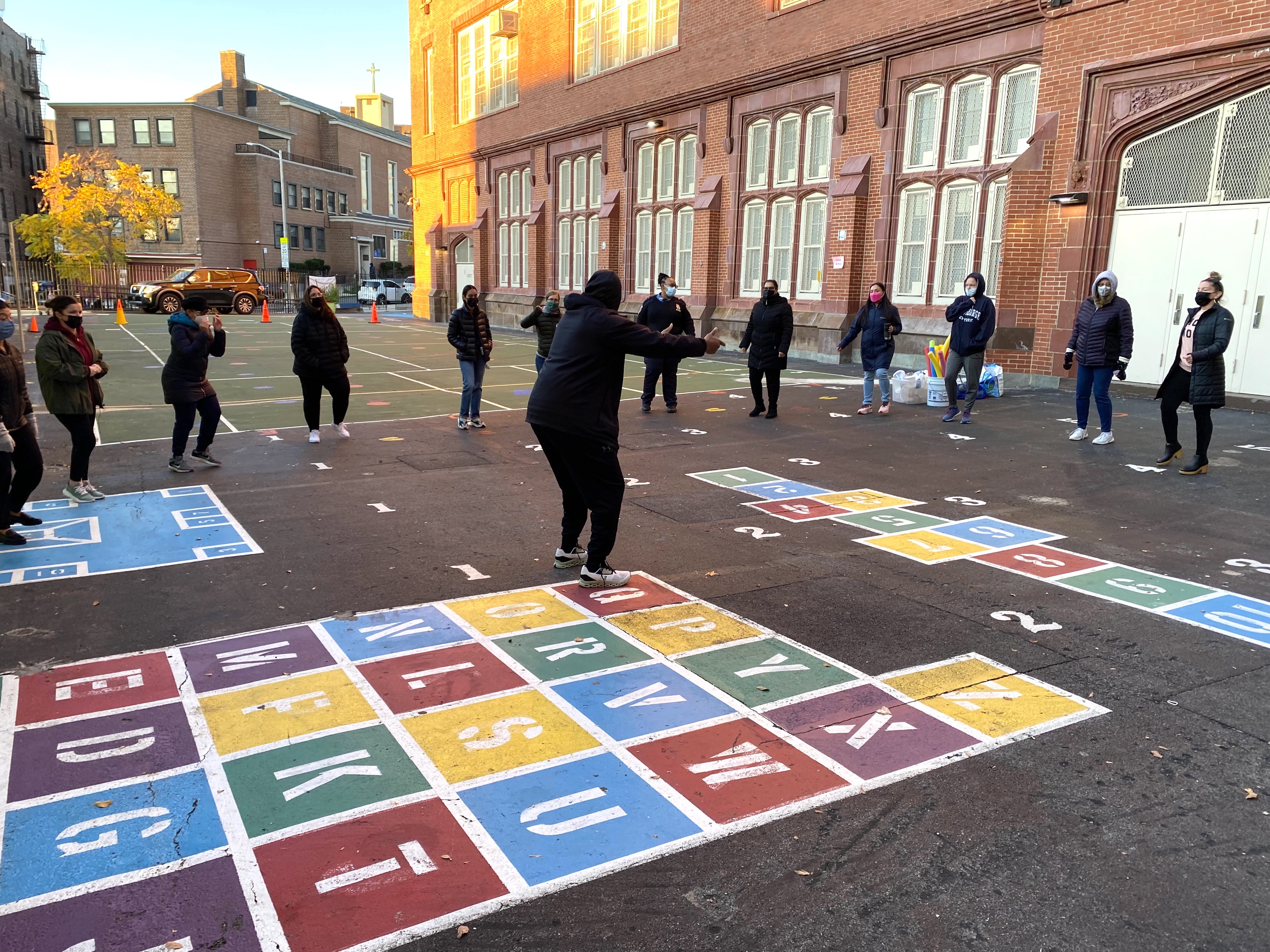 People engaged in an activity on a colorful playground with educational markings