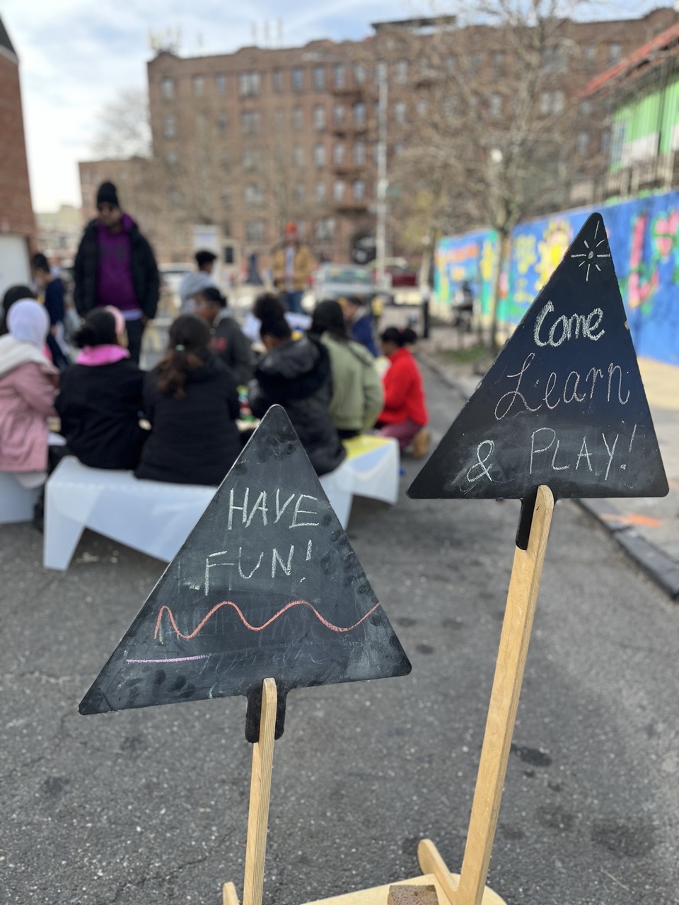 Community learning signs saying 'Come Learn & PLAY!' and 'HAVE FUN!'