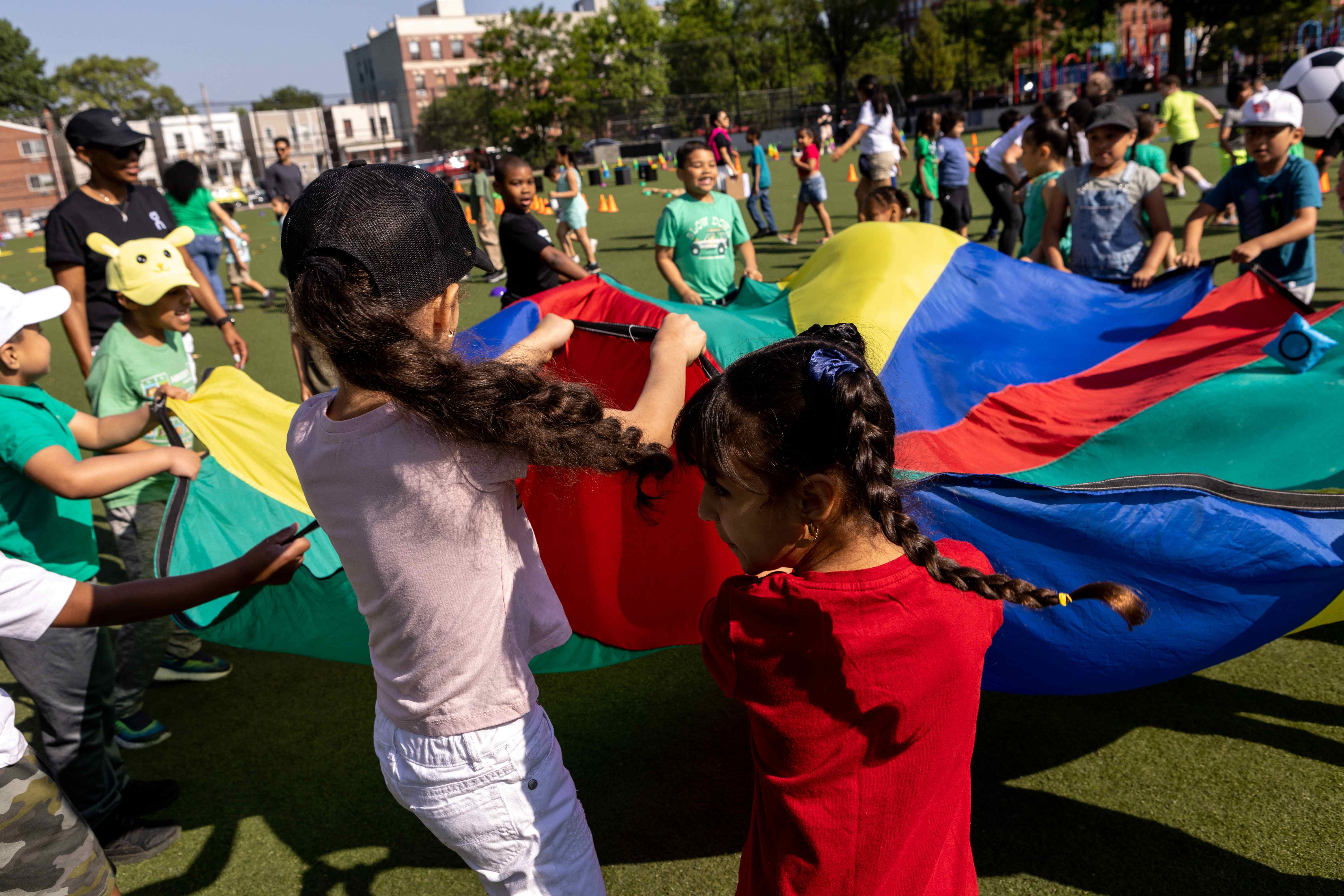 Children playing with a colorful parachute in a community field activity