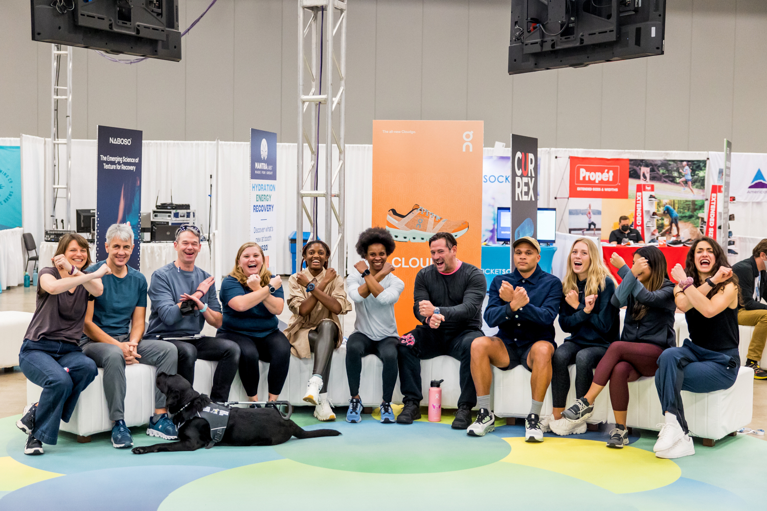 Diverse group of Right to Run program partners making X gestures at a convention