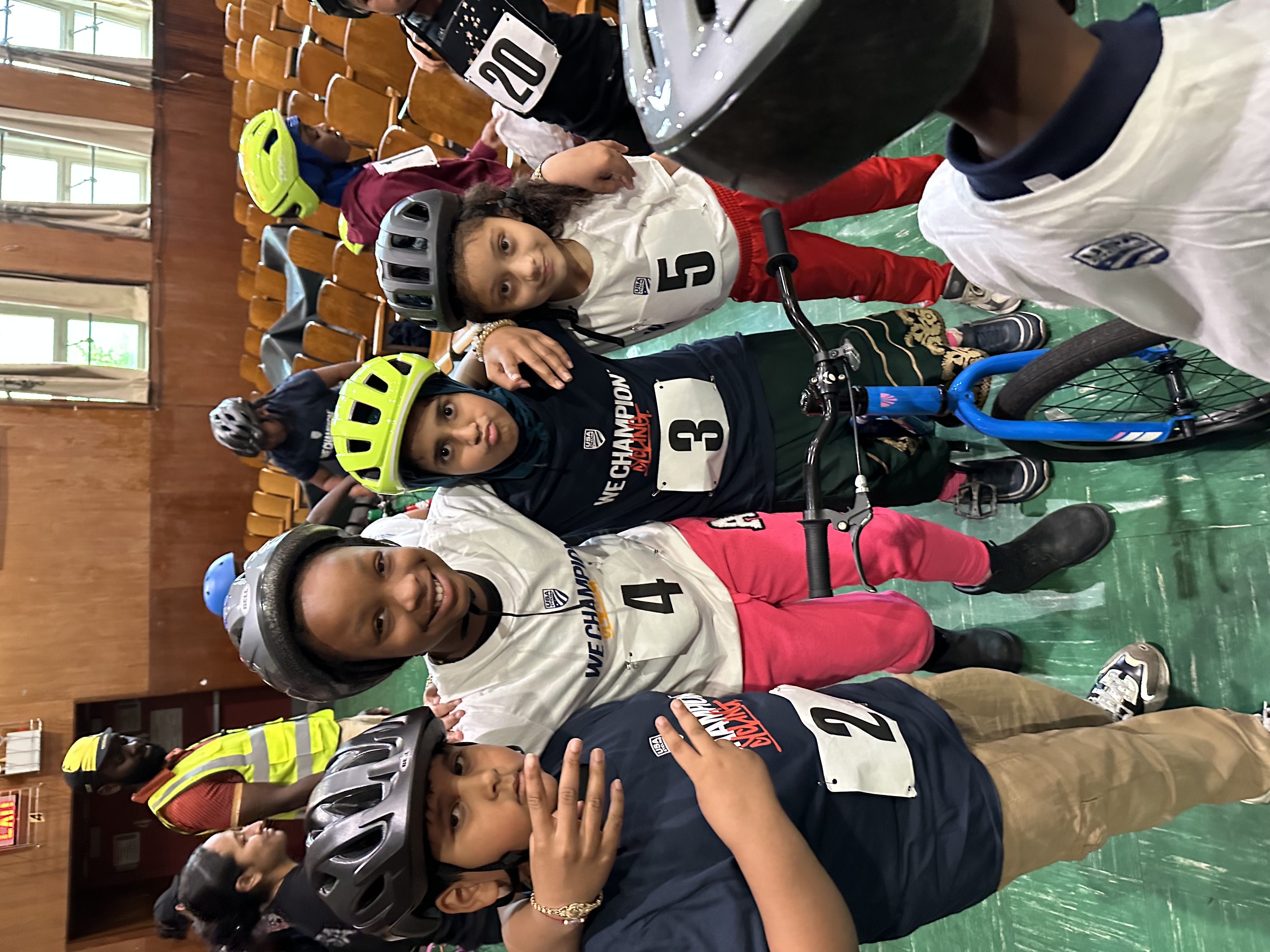 Young cyclists with numbered bibs posing together at a cycling event